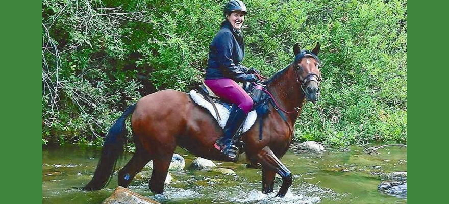 Denise Fissel on horseback in a river.
